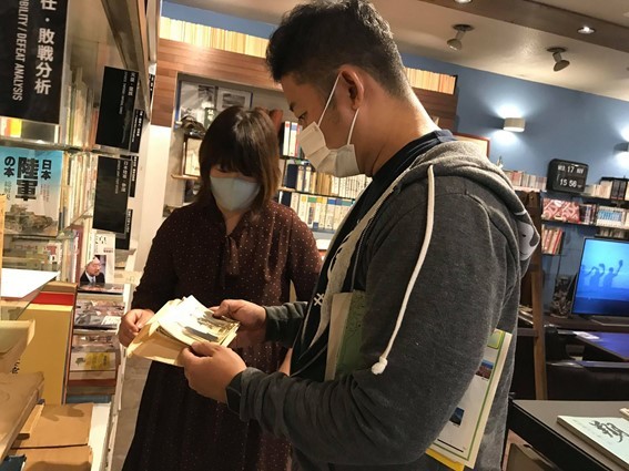 スタッフの堀口さんの説明を受ける筆者。近現代史が大好きな者同士、話が大いに盛り上がった。手にしているのは、昭和7年の上海天長節爆弾テロ事件の直前直後に撮影された生写真