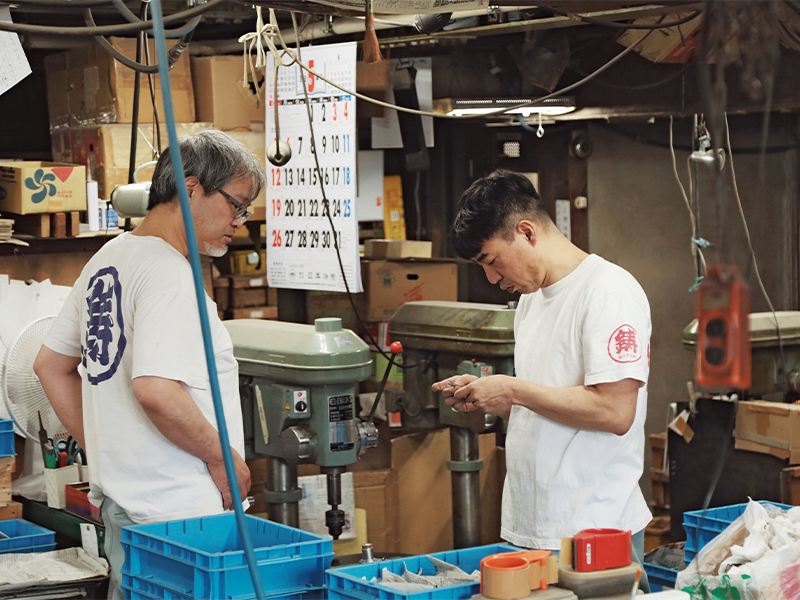 部品を確認する小池英貴さん(右)は、石川さんの師匠。