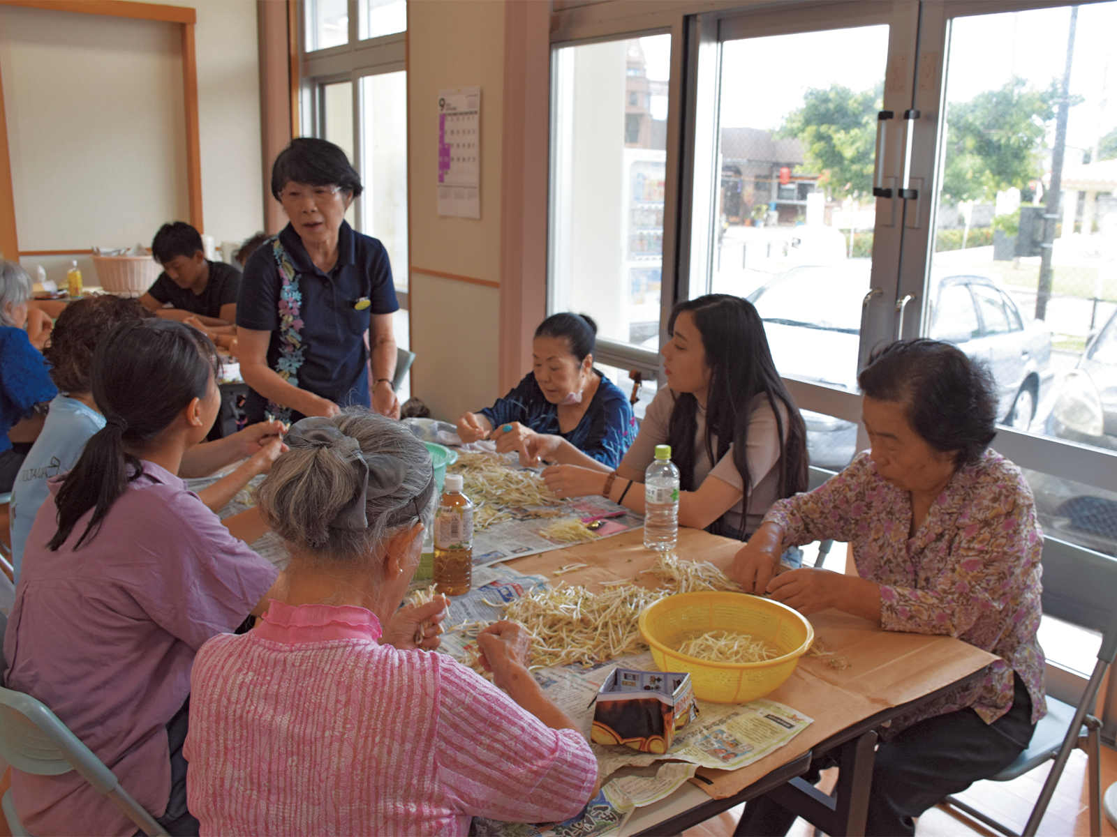 公民館のデイケアで「もやしのひげ取り」を行う高齢者とふれ合う。