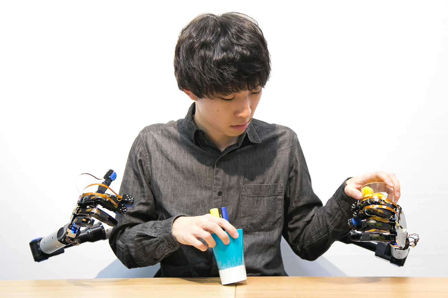 「MetaLimbs」の使い方に慣れれば、ボールも紙コップも掴むことができる。アームの先にハンダゴテをつければ、人間の身体能力を超える機能を付与できるという。