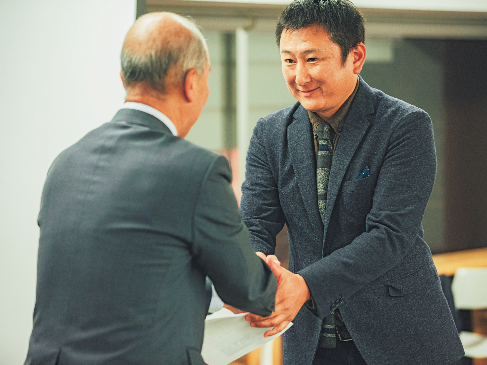 修了証を受け取り、副村長と握手を交わす受講生。