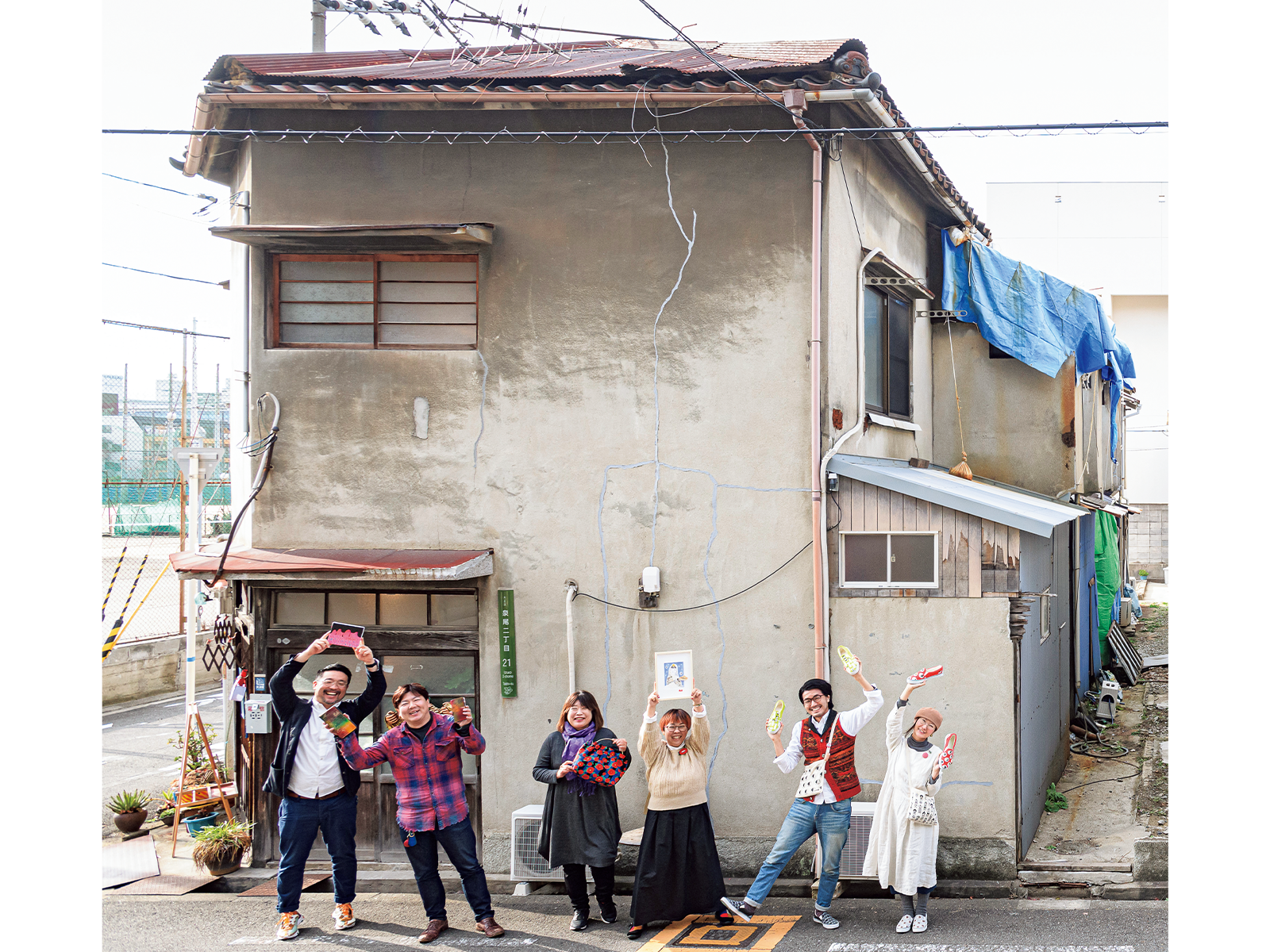 右ページの建物が『ヨリドコ大正メイキン』。左ページの建物は『gallery & stay 人魚棟』。もともと築65年の長屋だった「小川文化」をリノベーションしてオープン。立っているのはオーナーをはじめ、入居者や利用者のみなさん。