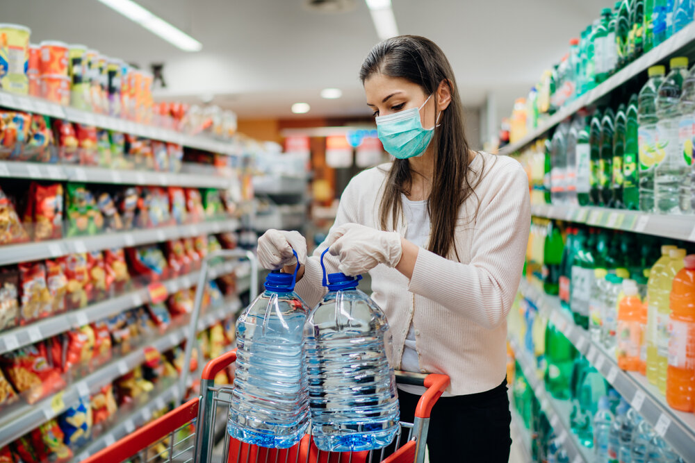 スーパーマーケットで水を買うマスクをした女性