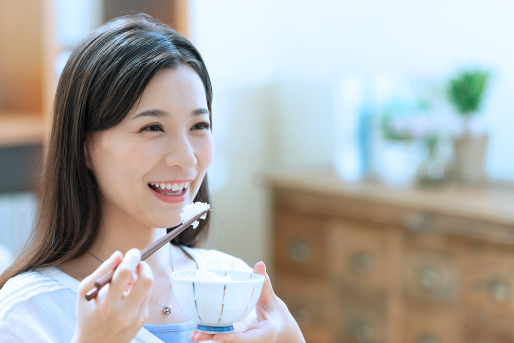 ご飯を口に運ぶ笑顔の女性