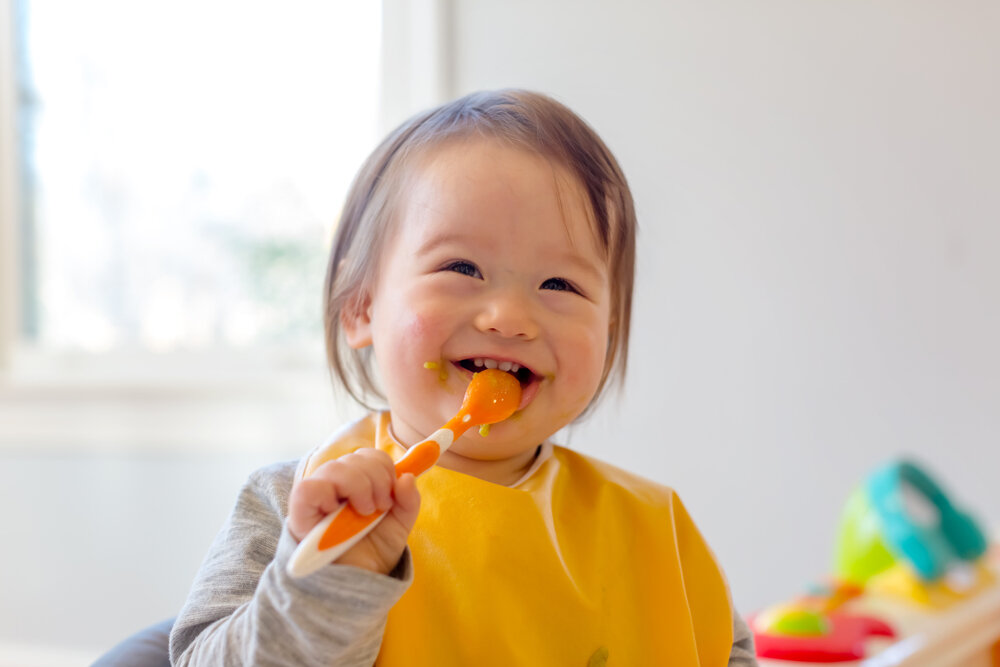 ご飯を食べながら微笑む赤ちゃん