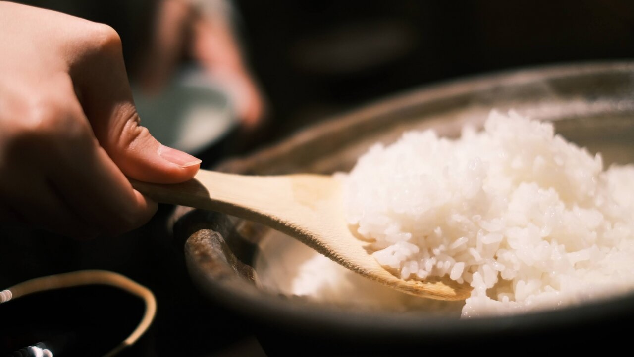 炊き立ての土鍋ご飯をしゃもじで混ぜる人