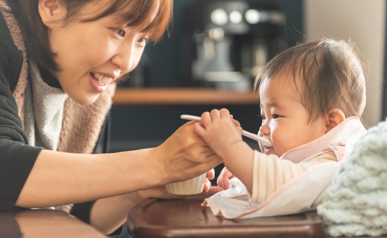 離乳食を食べる赤ちゃんと笑顔のママ
