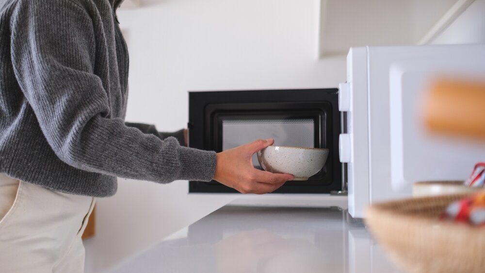 電子レンジにお椀を入れる女性