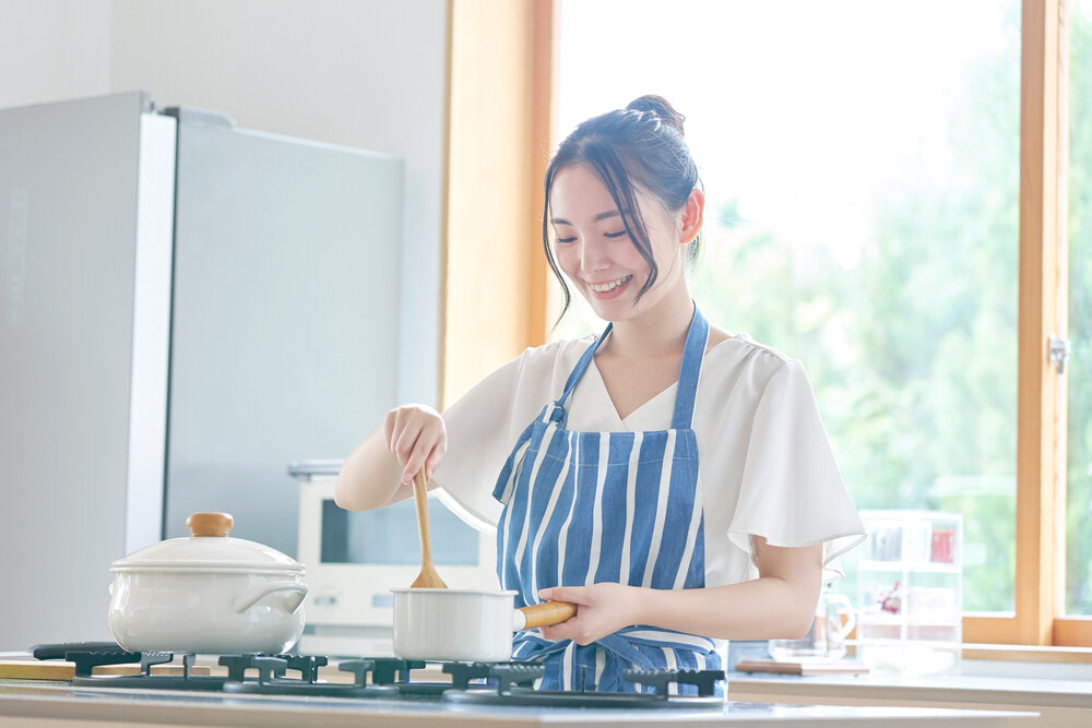 キッチンで笑顔で料理する女性