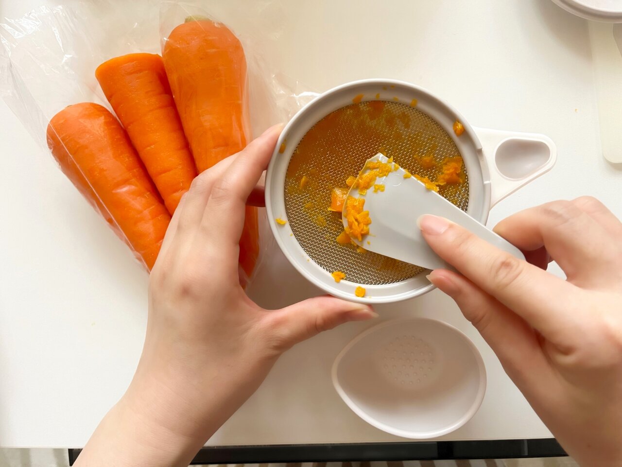 ニンジンをすり潰す女性の手元