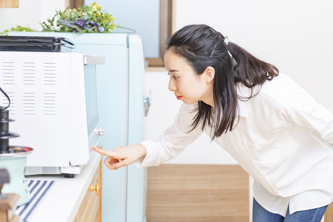 キッチンで電子レンジを操作する女性