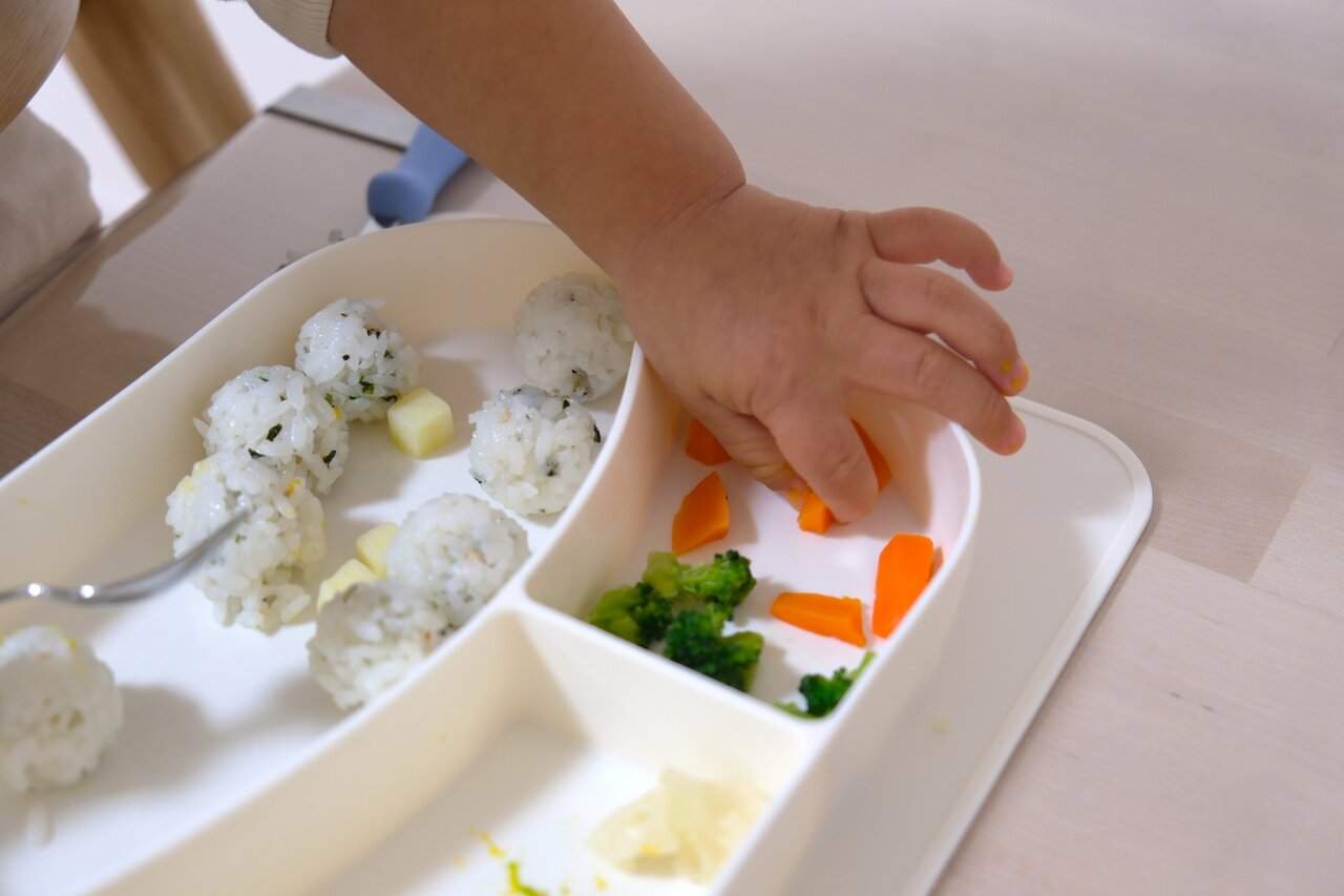 離乳食のにんじんを食べようとする赤ちゃん