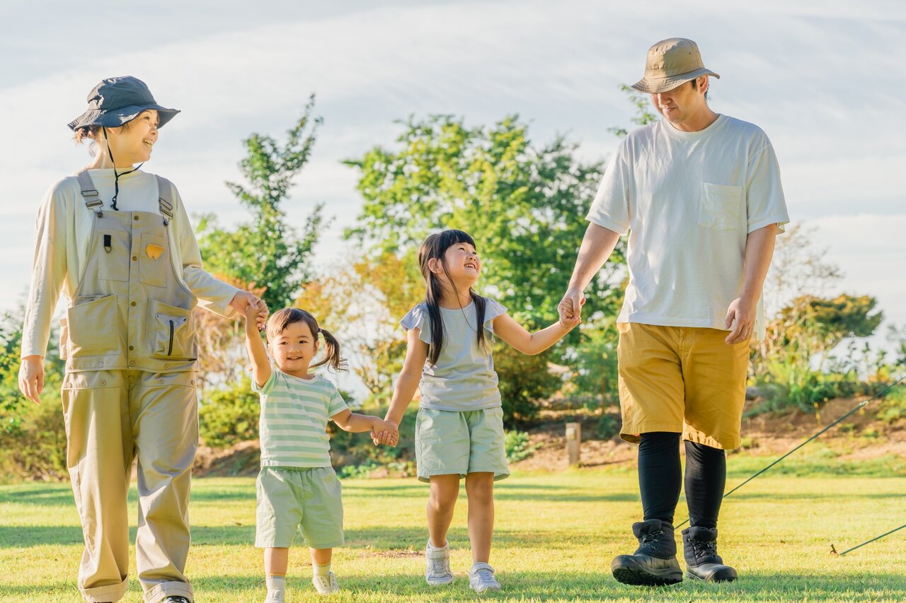 キャンプ場で手をつないで歩く家族