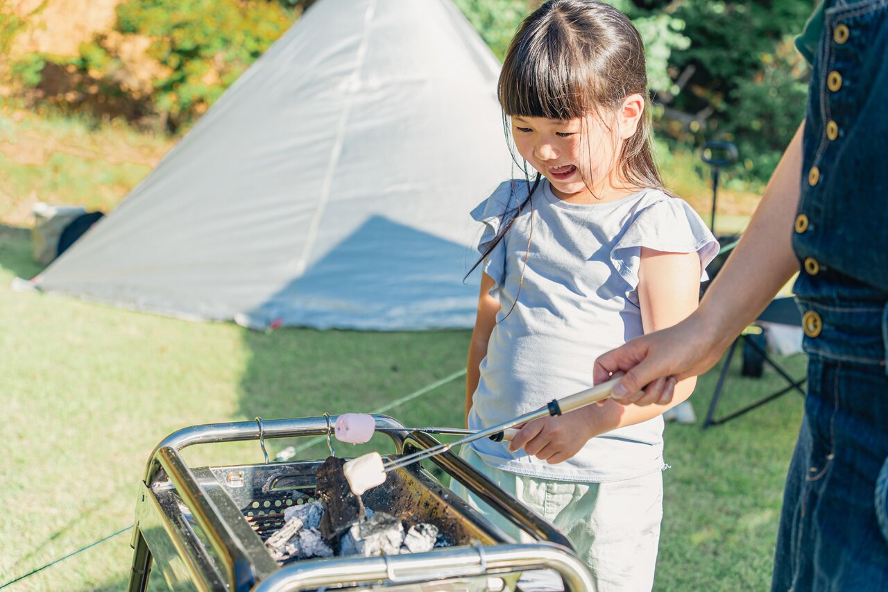 キャンプ場でマシュマロを焼く女の子