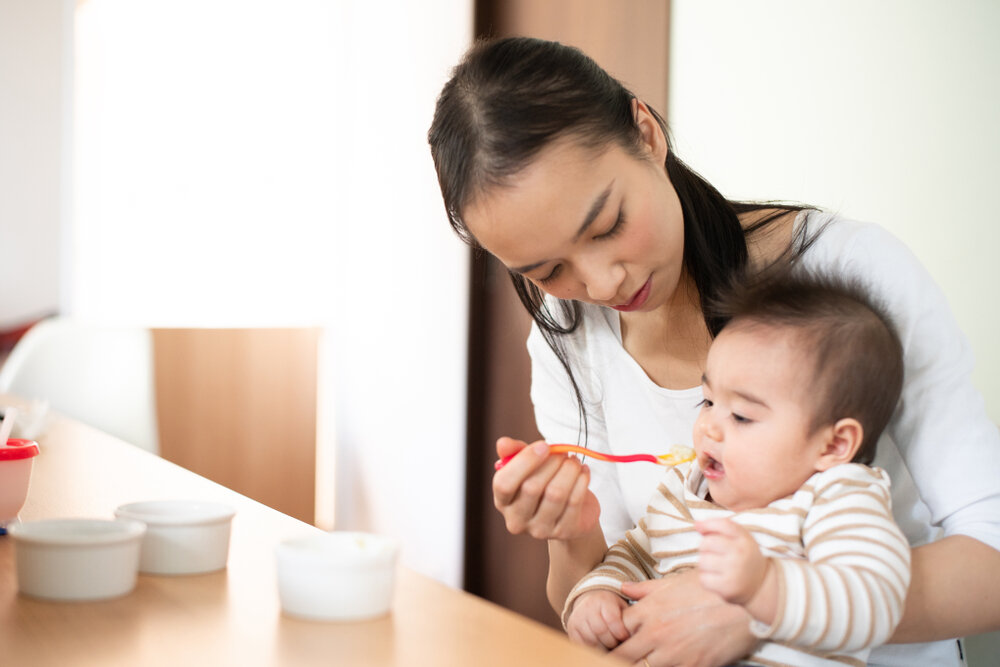 赤ちゃんに離乳食をあげているママ
