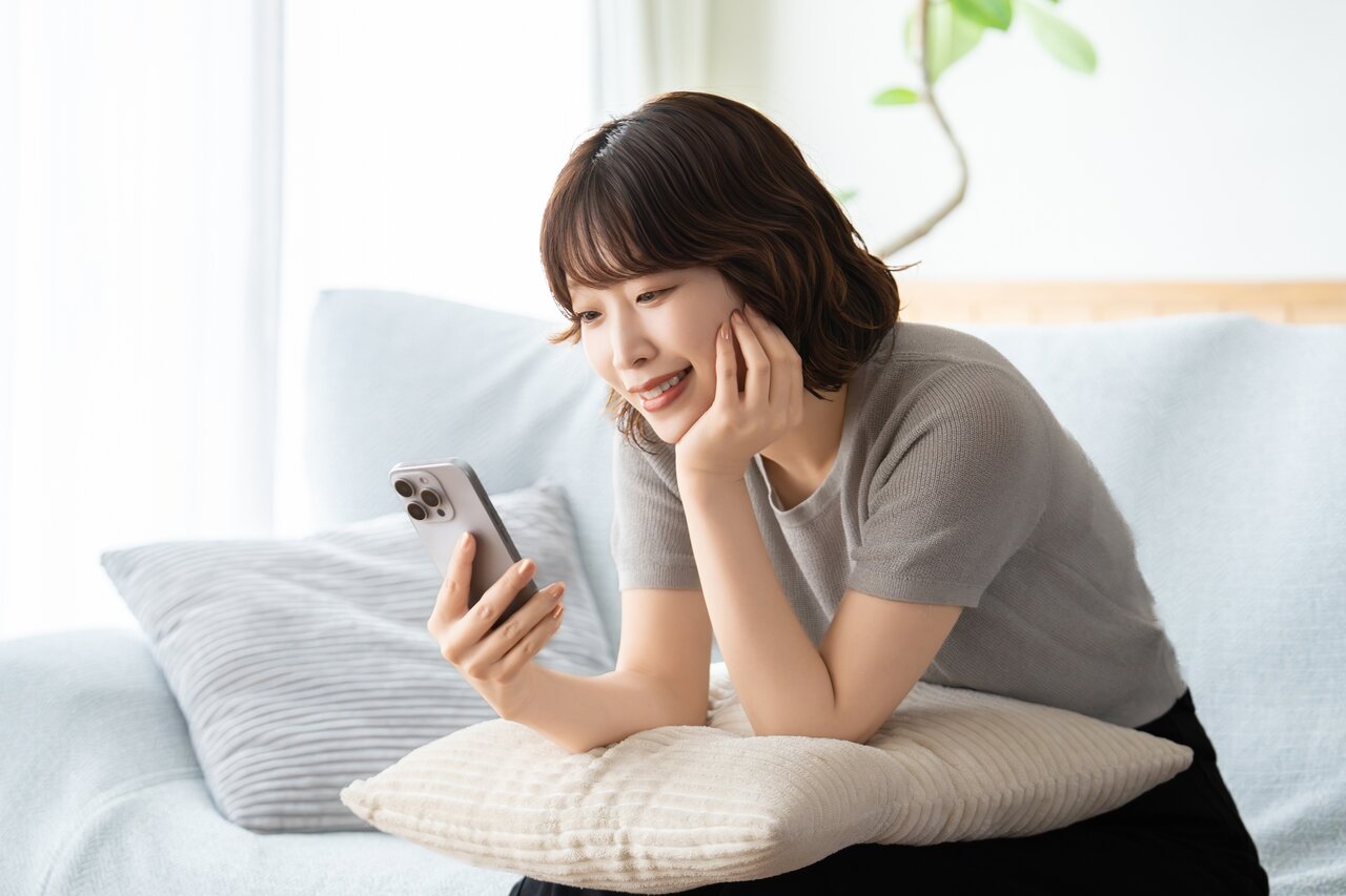 ソファに座ってスマートフォンを眺める女性