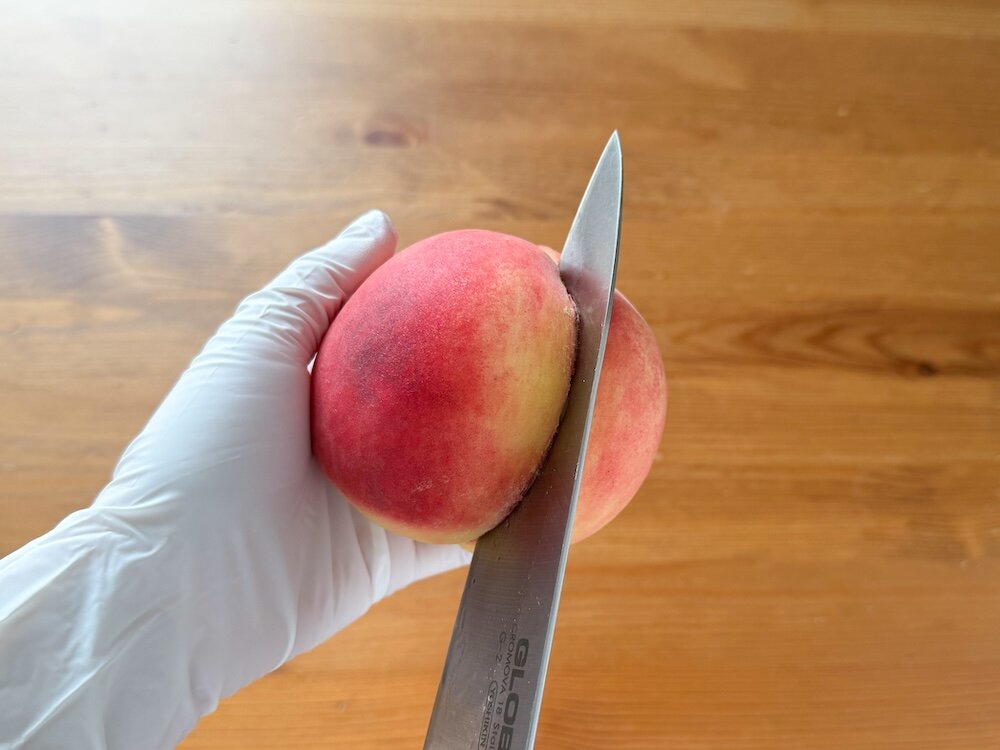 桃の背に包丁で切り込みを入れている画像