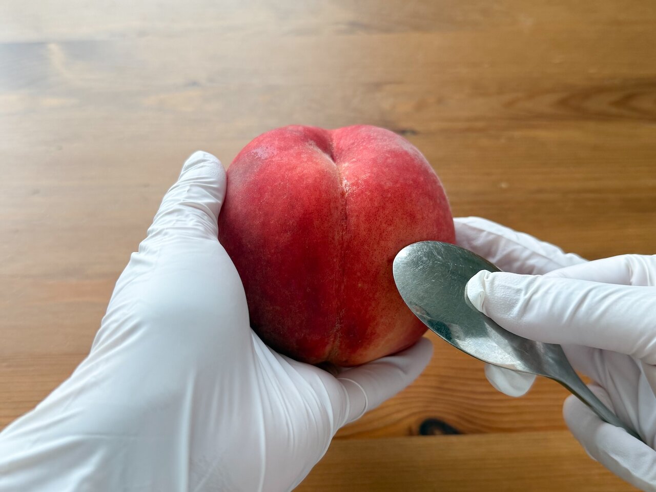 桃の皮をたるませてからむく　桃をスプーンで擦る