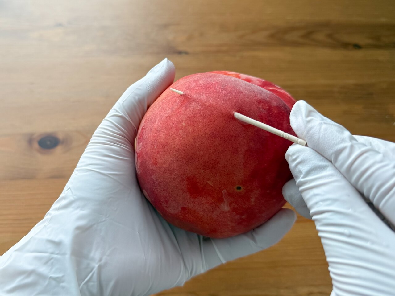 桃の果肉と皮の間に爪楊枝を滑り込ませるように通す