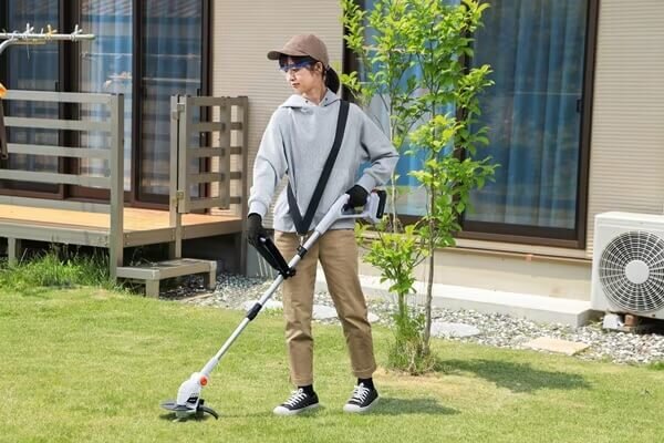 電動トリマーで草を刈る女性