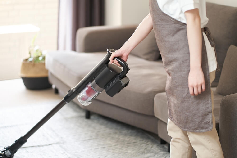 スティック型掃除機を使用している女性