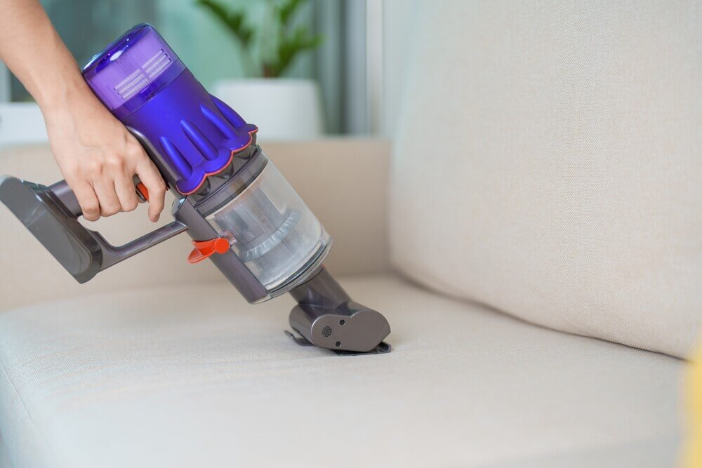 ハンディ型掃除機で掃除をする女性