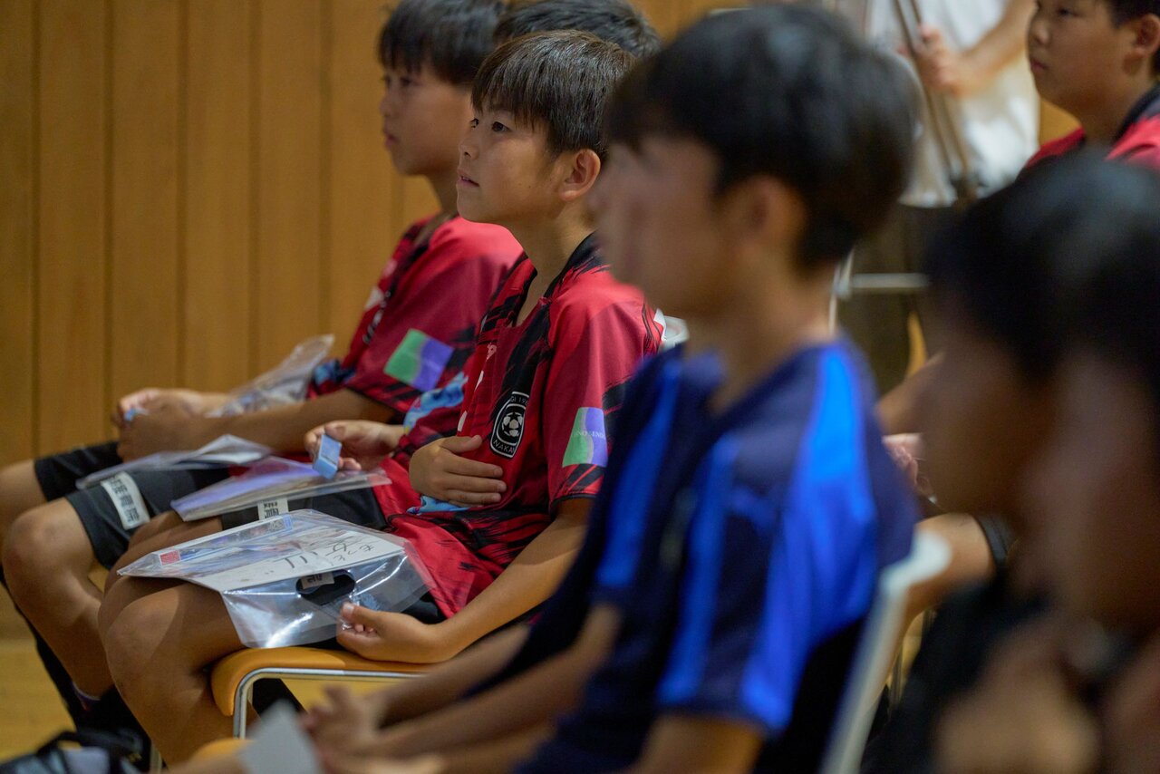 プレミアリーグU-11の「震災学習プログラム」で話を聞く子どもたち