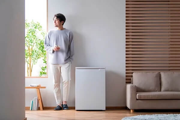 白い冷蔵庫の横に立つ男性
