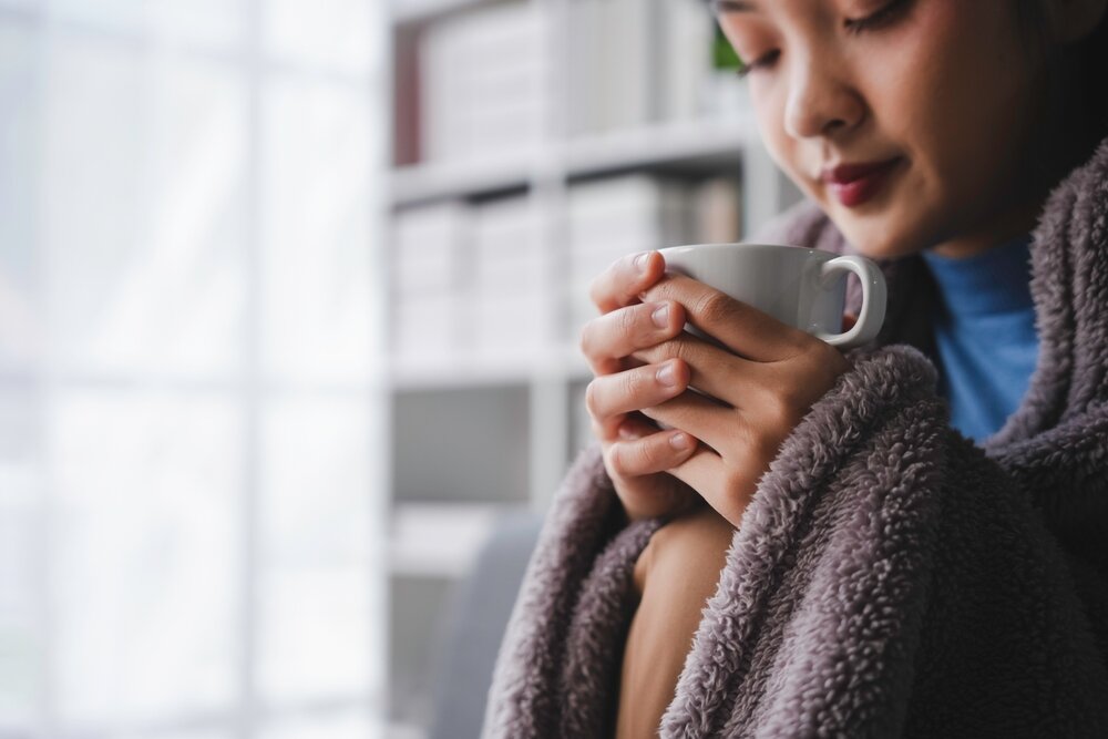 電気毛布をはおり温まる女性