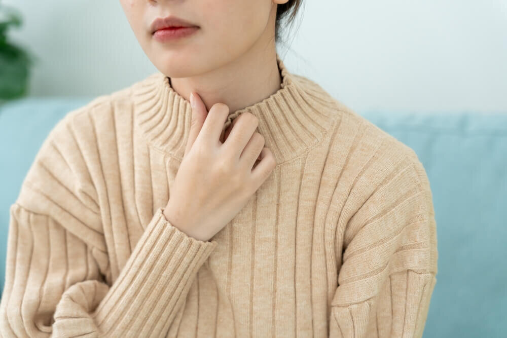 喉に手をあてる女性