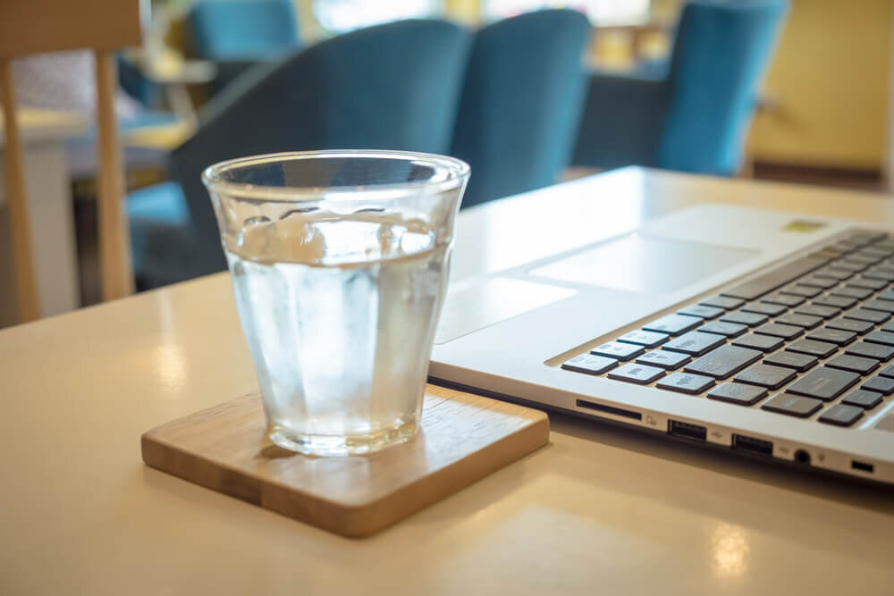 パソコンのそばに置かれた水の入ったコップ