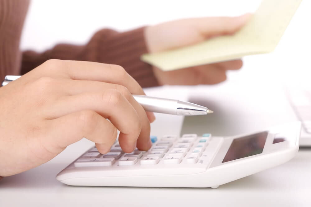 計算機を使って計算をする女性の手元