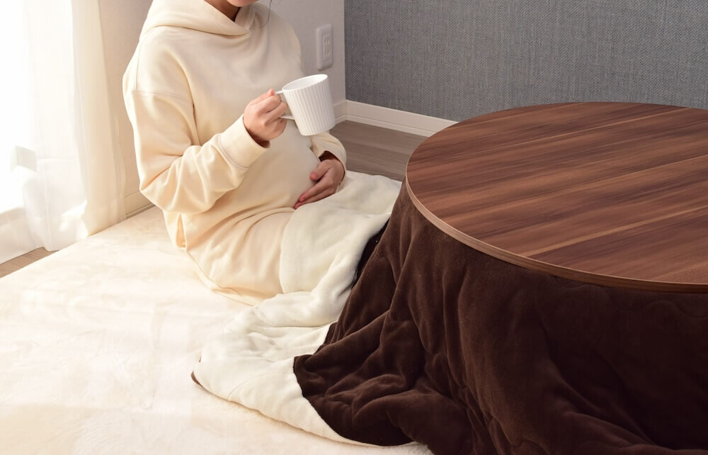 こたつに入ってドリンクを飲む女性