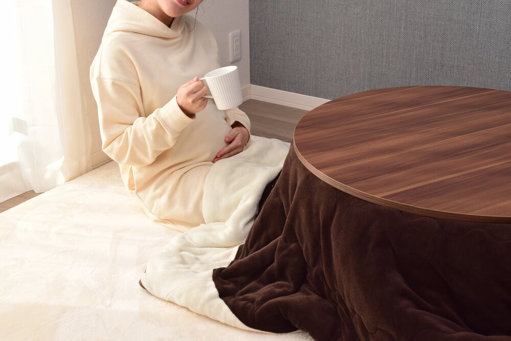こたつでお茶を飲む女性