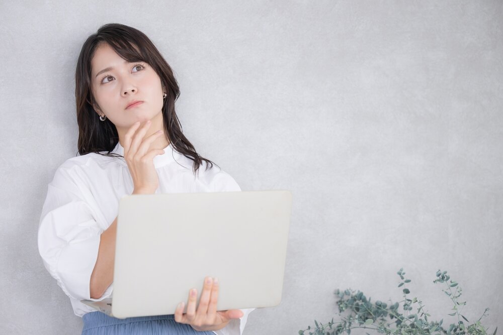 パソコン片手に悩む女性