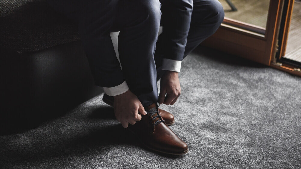 革靴を履こうとするスーツを着た男性