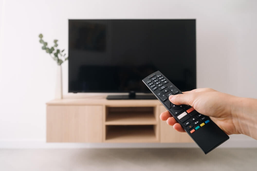 テレビのリモコンを持つ人の手元