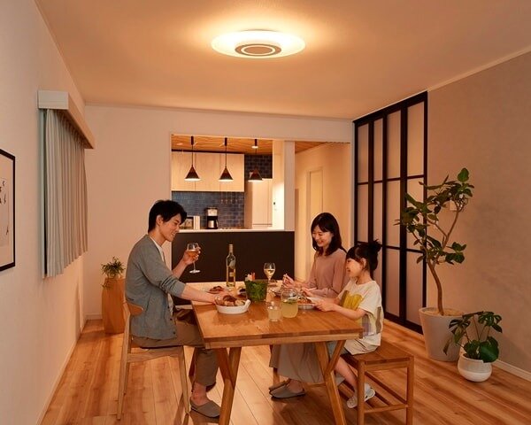 温かみのある照明のリビングで食卓を囲む家族