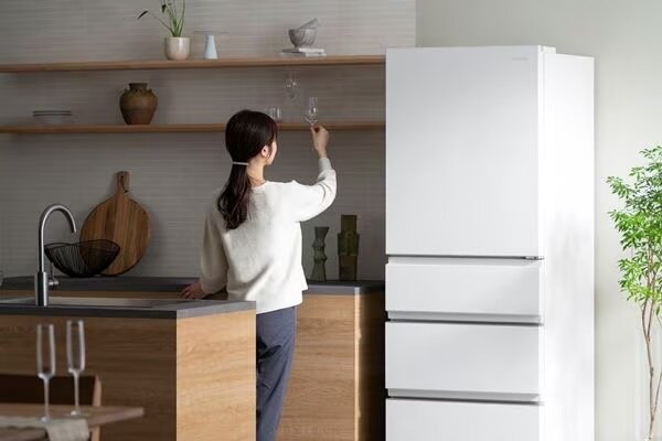 冷蔵庫の横でグラスを持ち上げる女性