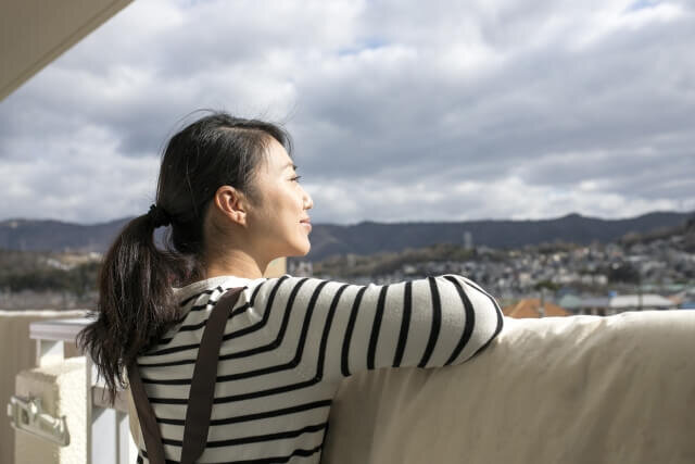 ベランダに布団を干す女性
