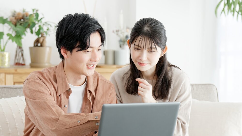 パソコン画面を確認しながら会話をするカップル