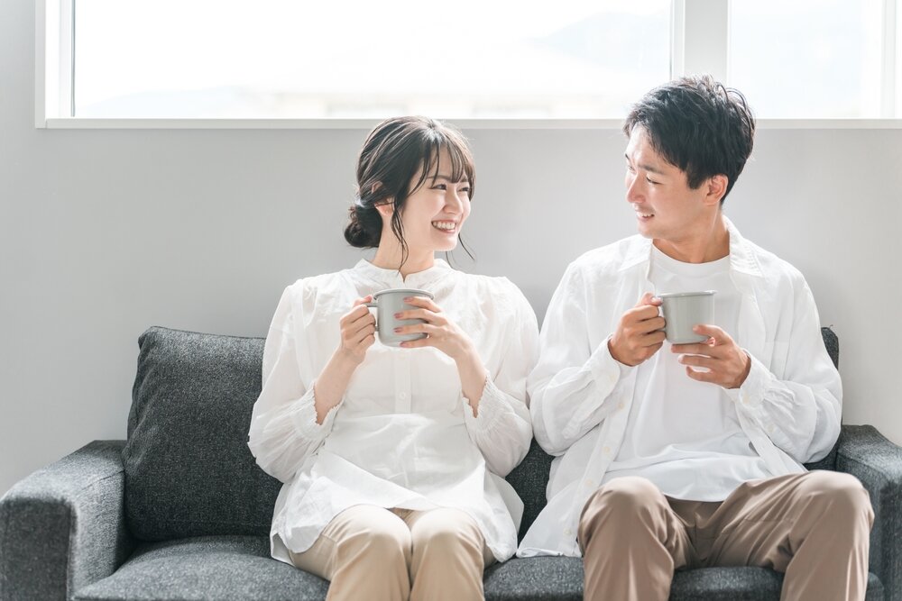 ソファで飲み物を片手にくつろぐカップル