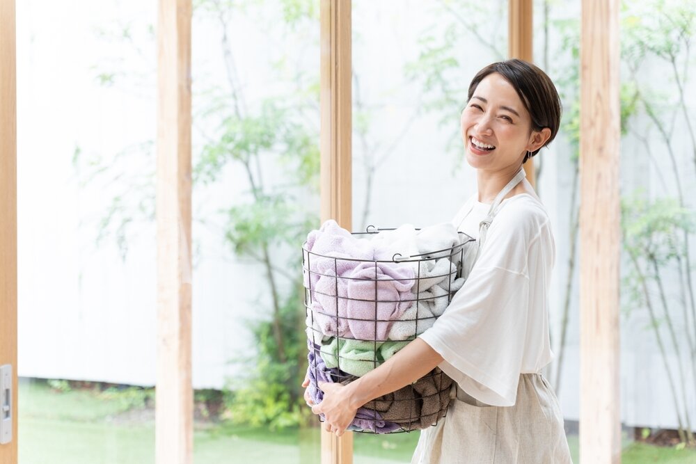 洗濯かごを持つ笑顔の女性