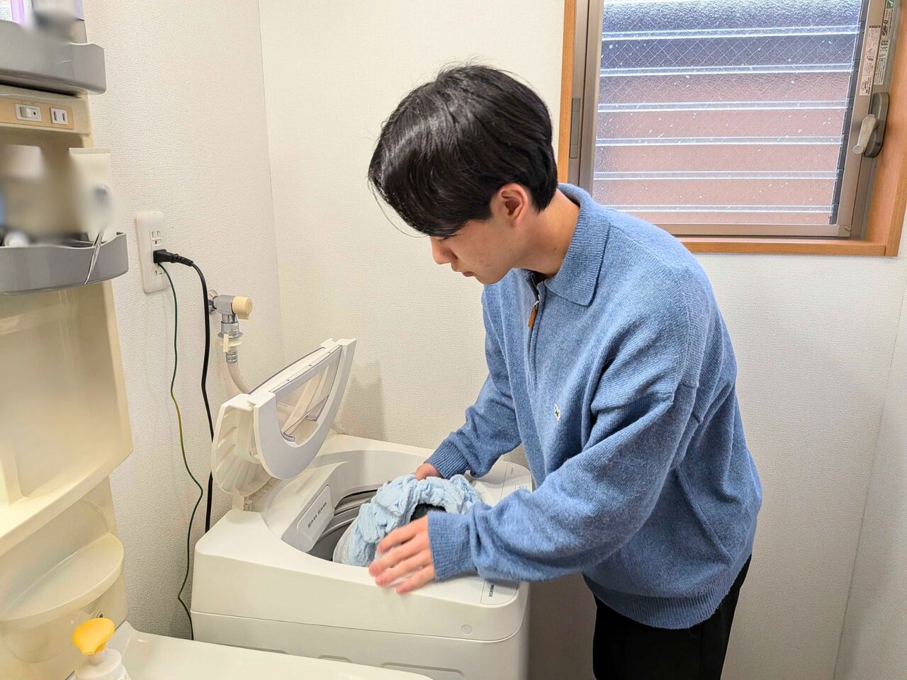 洗濯ものをいれる男性