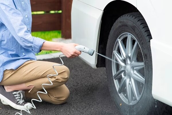 アイリスオーヤマのポータブルウォッシャーで洗車する男性