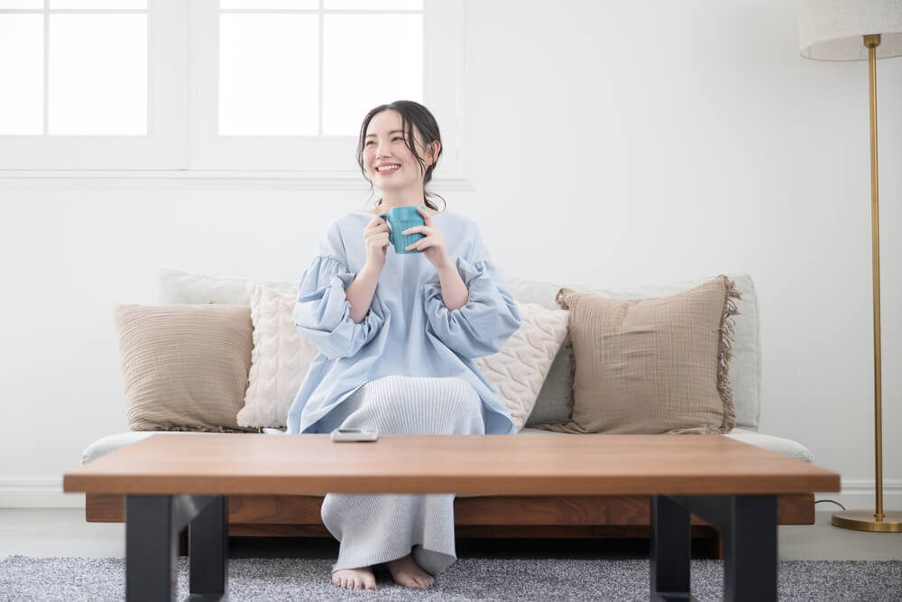 ソファで飲み物を飲む女性