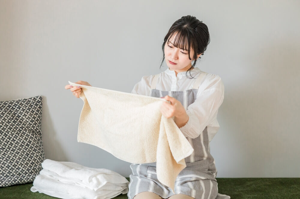 洗濯物を広げて首を傾げる女性