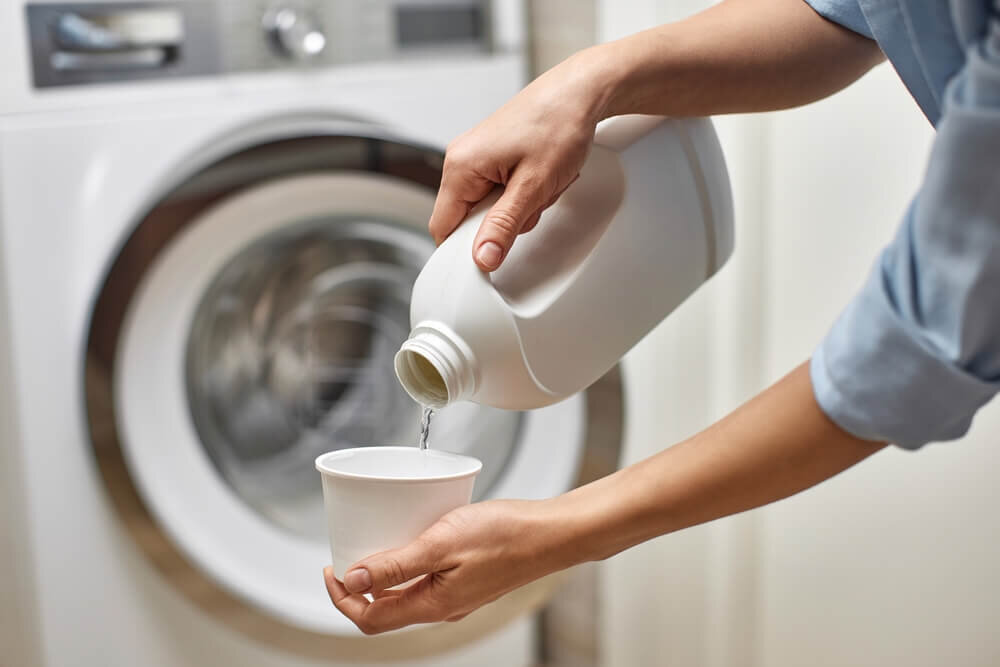 洗濯機の洗剤をカップに入れる人の手