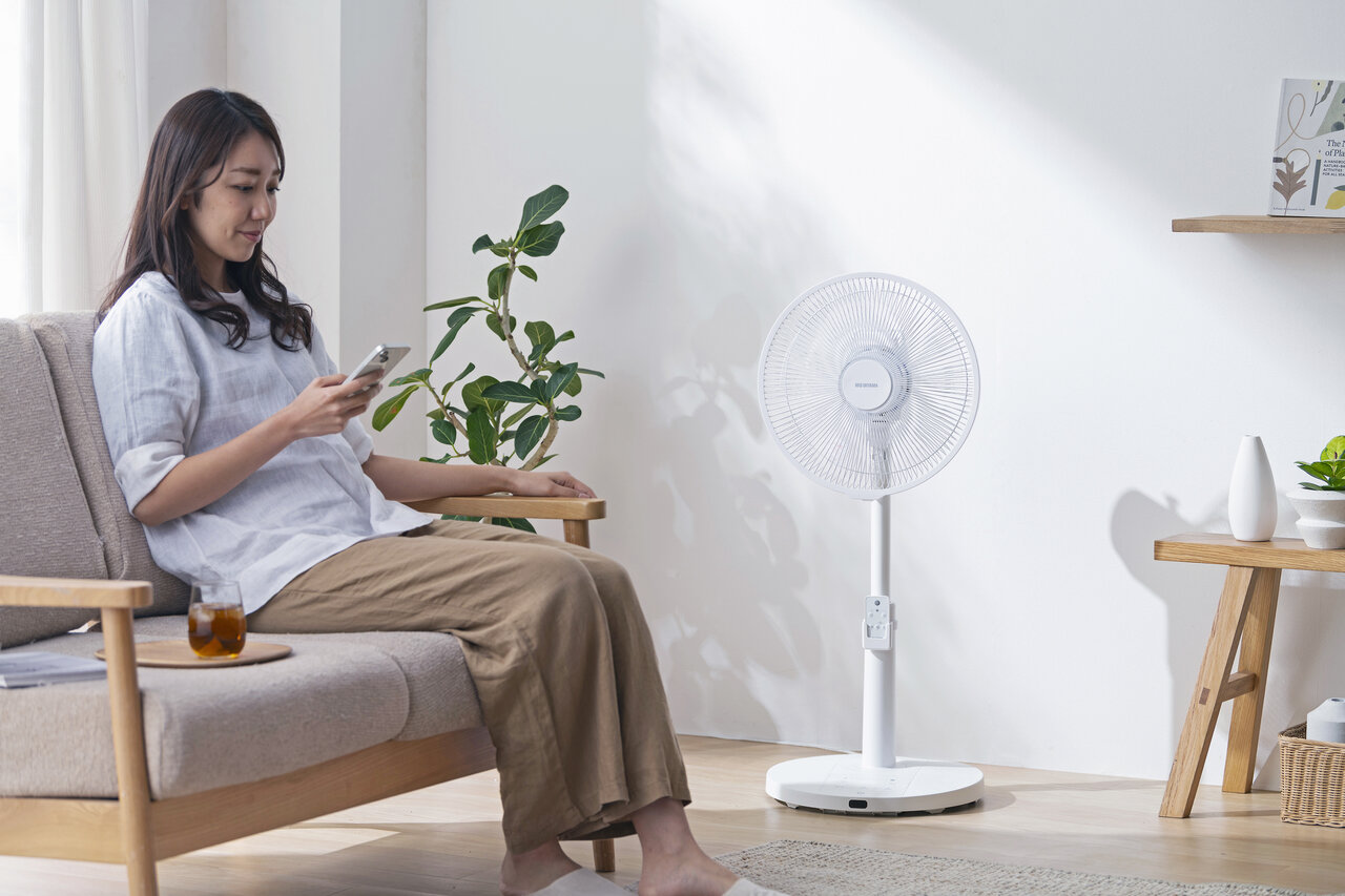 扇風機の風にあたる女性