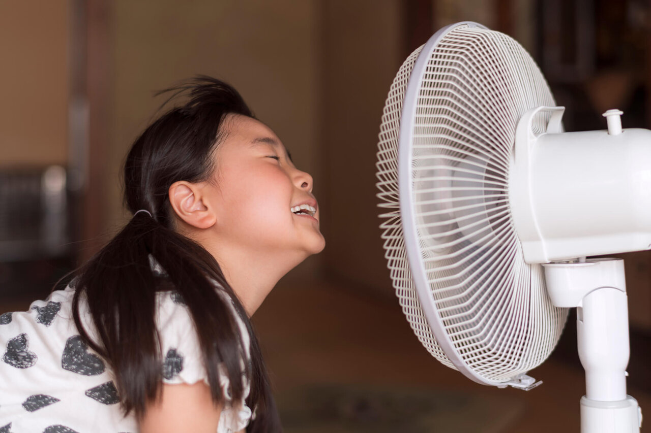 扇風機の風にあたる少女